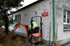 Mężczyzna kopie przy szkole mini koparką