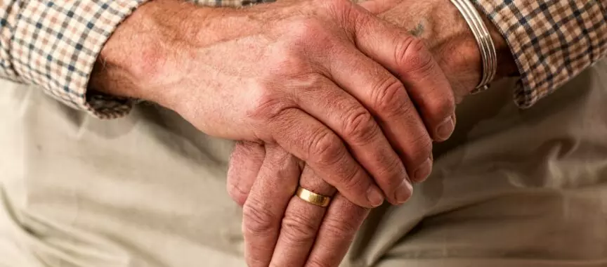 Założona ręka na rękę osoby starszej.