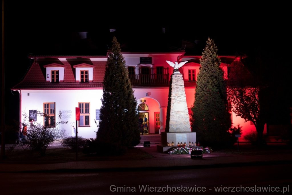 Zdjęcie nocą budynku Domu Ludowego w Wierzchosławicach oświetlonego w kolorach biało czerwonych