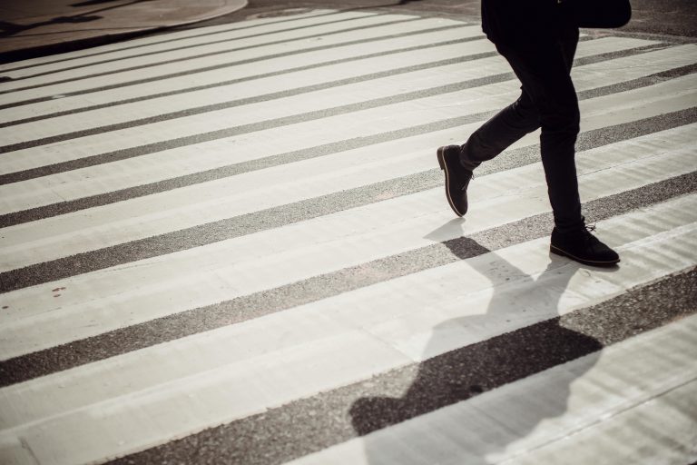 Zdjęcie przedstawia człowieka przechodzącego przez przejście dla pieszych.